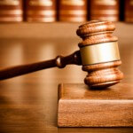 Gavel and sounding block on desk with books seen in the background.