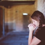 High School Student Praying in a Corridor.